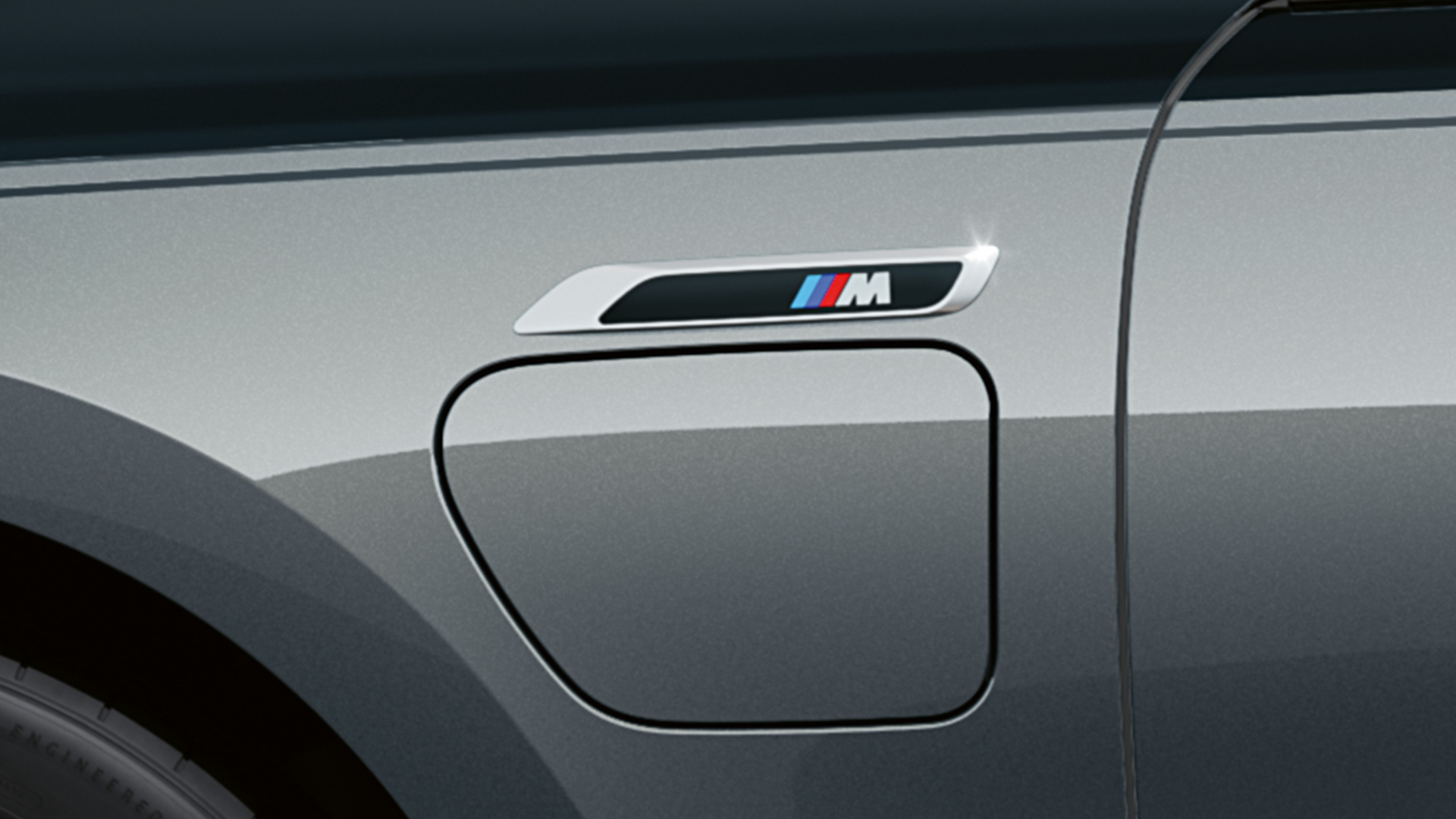 M Badge i BMW M760e xDrive Sedan G70 M Badge BMW M760e xDrive Sedan G70 M Performance-pakke BMW Individual Two-Tone-lakkering safirsort metallic BMW Individual dravittgrå metallic nærbilde sett fra siden