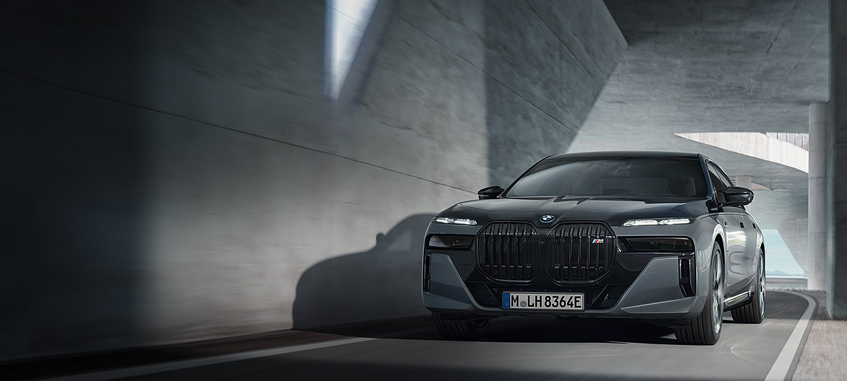 BMW M760e xDrive Sedan G70 M Performance-pakke BMW Individual Two-Tone-lakkering safirsort metallic BMW Individual dravittgrå metallic sett skrått forfra kjørende på vei