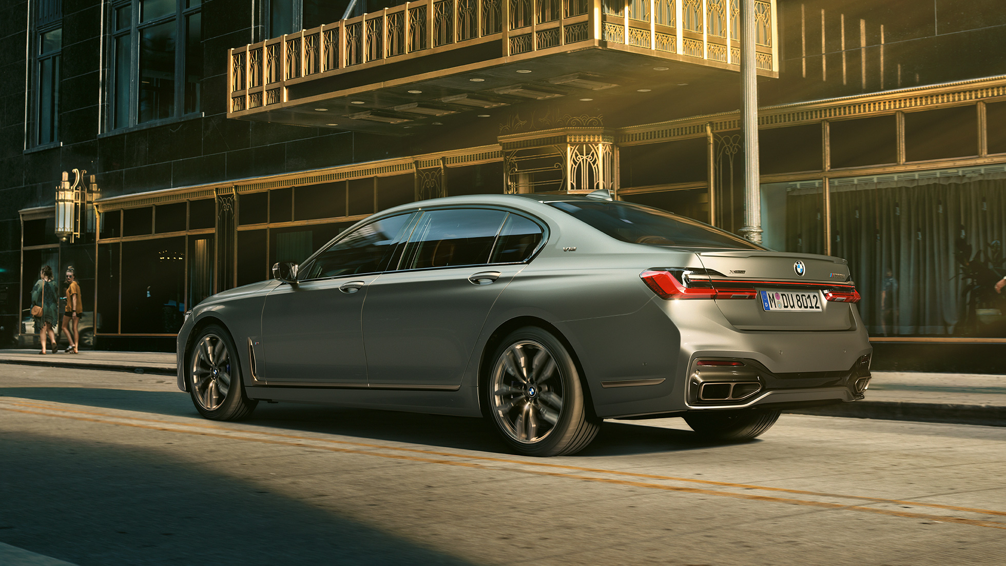 BMW M760Li xDrive sedan med V12-motor BMW M760Li xDrive som står foran skyskrapere i bylandskap, sett fra siden bakfra