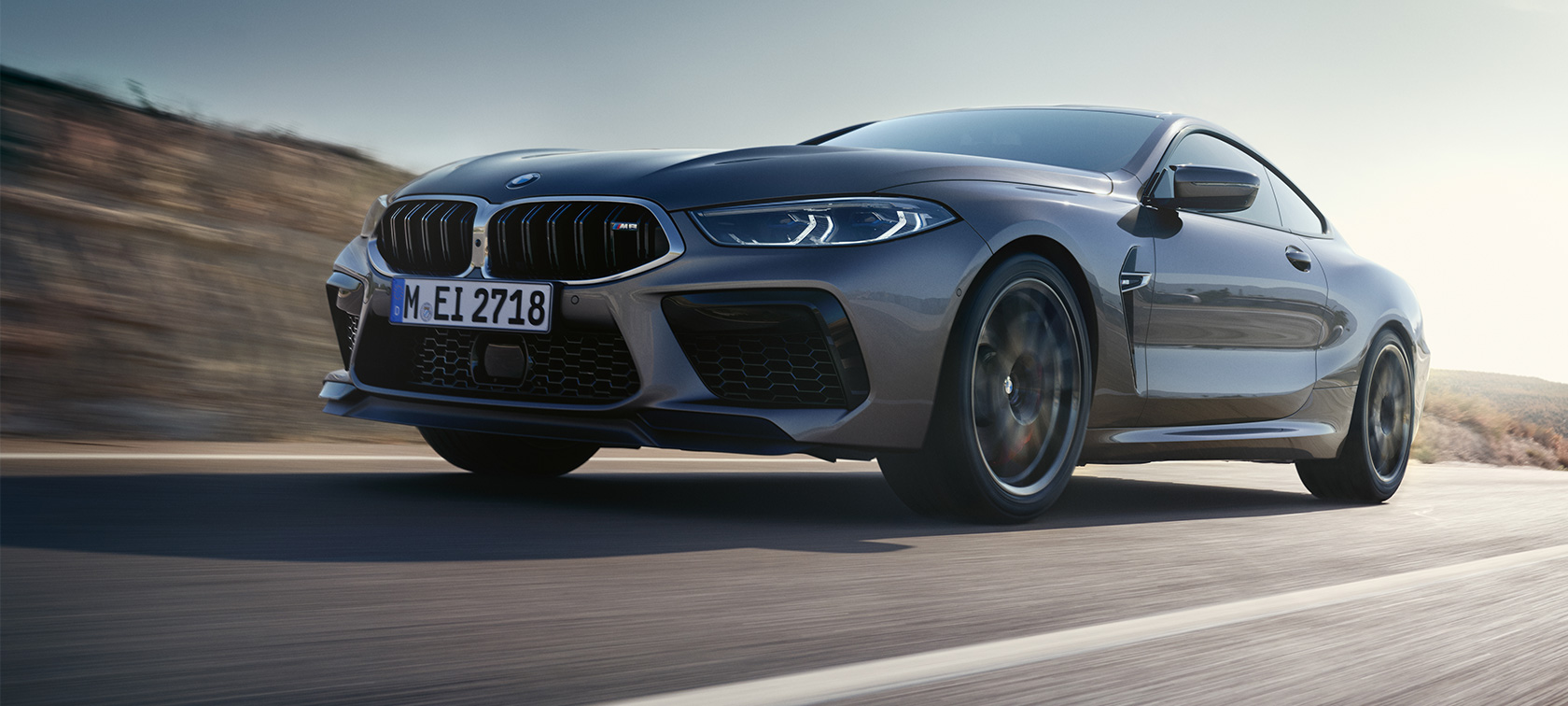 BMW M8 Coupé F92 LCI Facelift 2022 sett skrått fra siden i under kjøring BMW M8 Coupé F92 LCI Facelift 2022 Skyscraper-grå metallic sett skrått fra siden i froskeperspektiv under kjøring