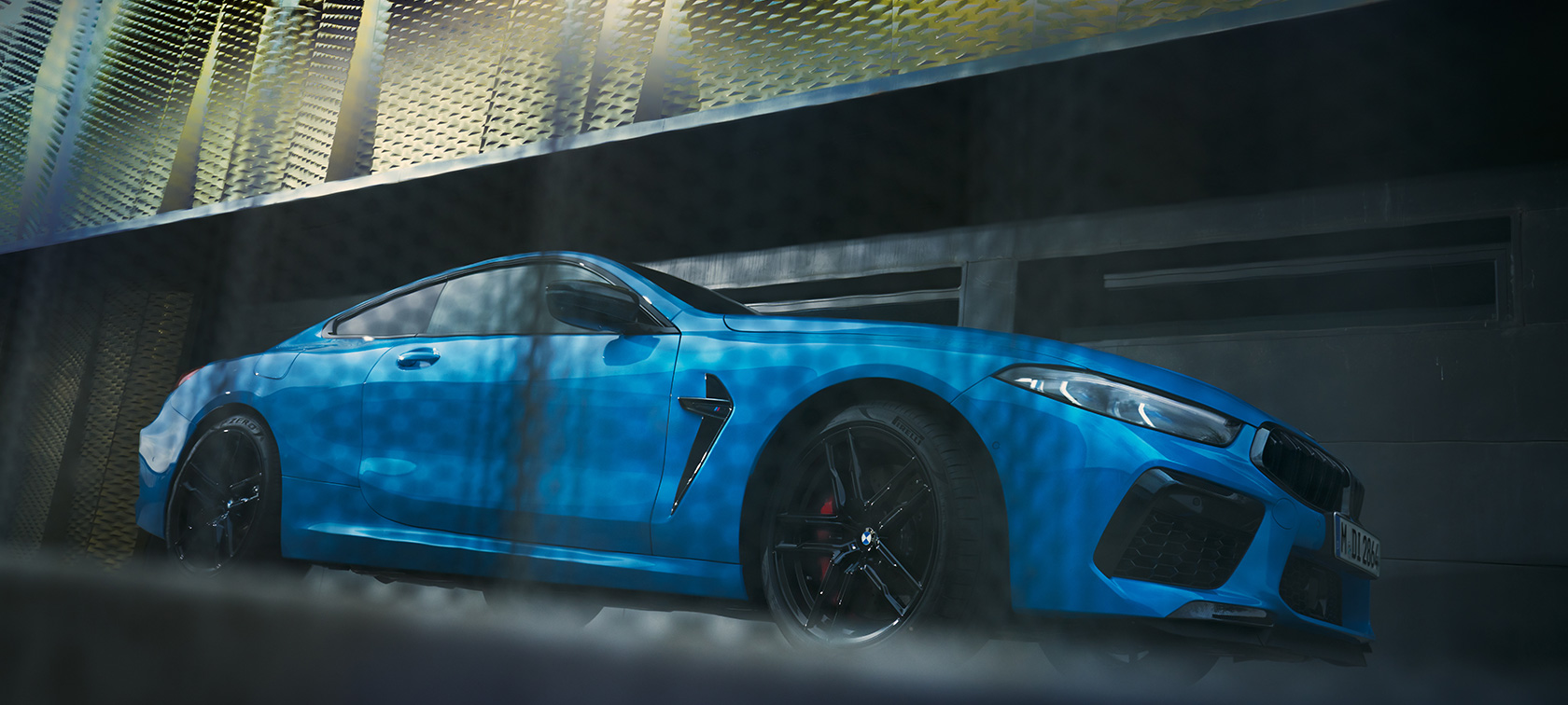 BMW M8 Competition Coupé F92 LCI Facelift 2022 sett i froskeperspektiv fra siden BMW M8 Competition Coupé F92 LCI Facelift 2022 BMW Individual Daytona Beach-blå sett i froskeperspektiv fra siden parkert foran bygning