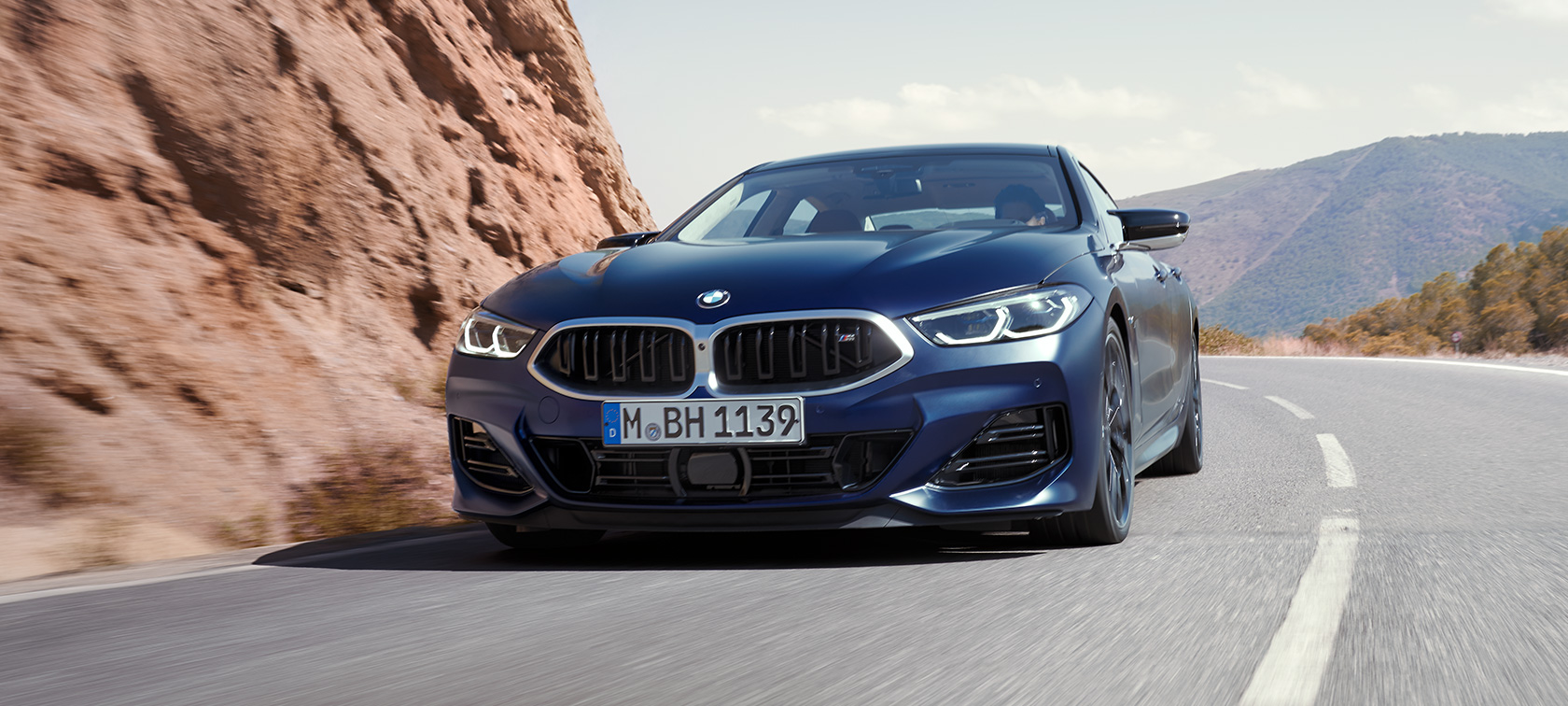 Sett på skrått forfra, kjørende BMW M850i xDrive Gran Coupé G16 LCI Facelift 2022 BMW M850i xDrive Gran Coupé G16 LCI Facelift 2022 BMW Individual Frozen Tanzanittblått metallic sett på skrått forfra kjørende rundt en sving