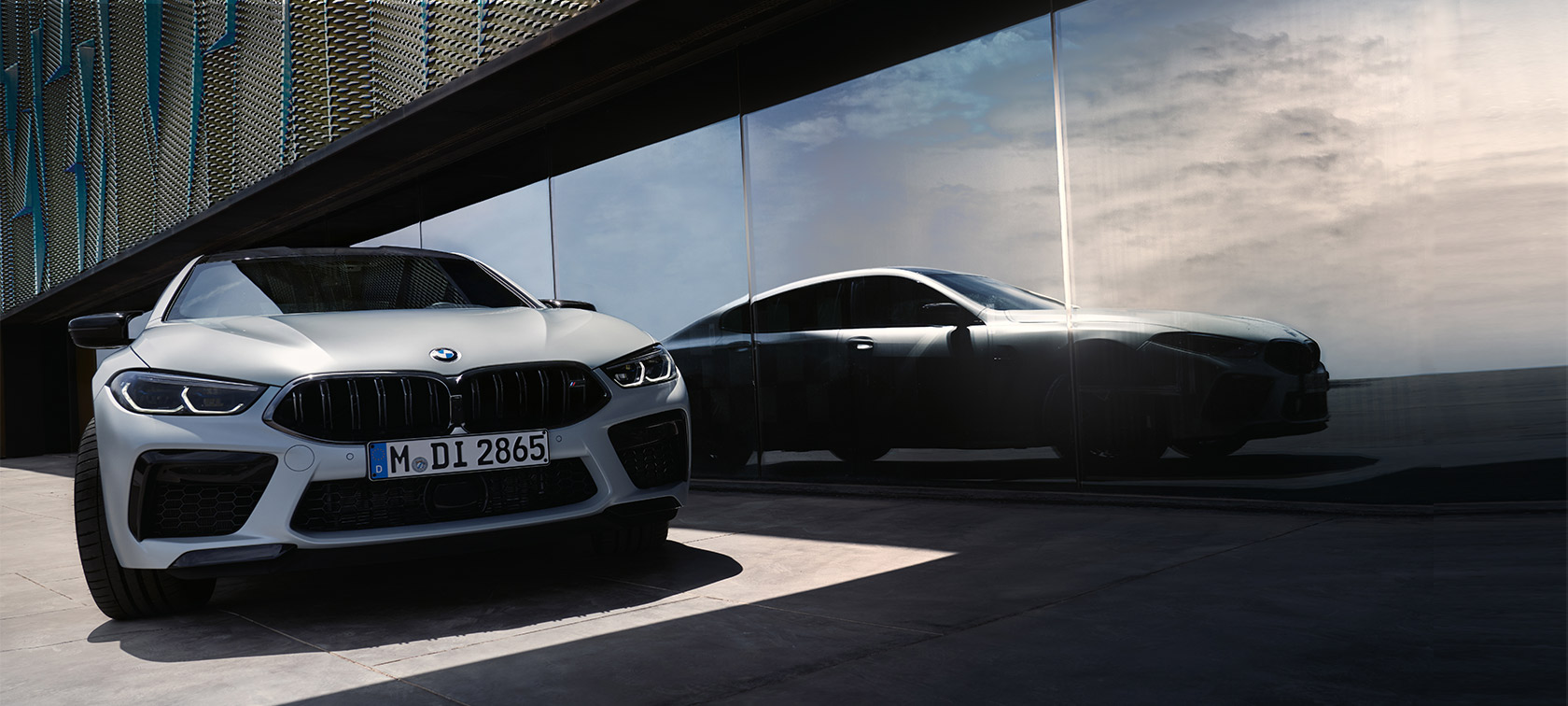 Sett forfra BMW M8 Competition Gran Coupé F93 LCI Facelift 2022 BMW M8 Competition Gran Coupé F93 LCI Facelift 2022 BMW Individual BMW Individual Frozen Brilliant White metallic sett forfra med refleksjon av silhuetten i et vindu