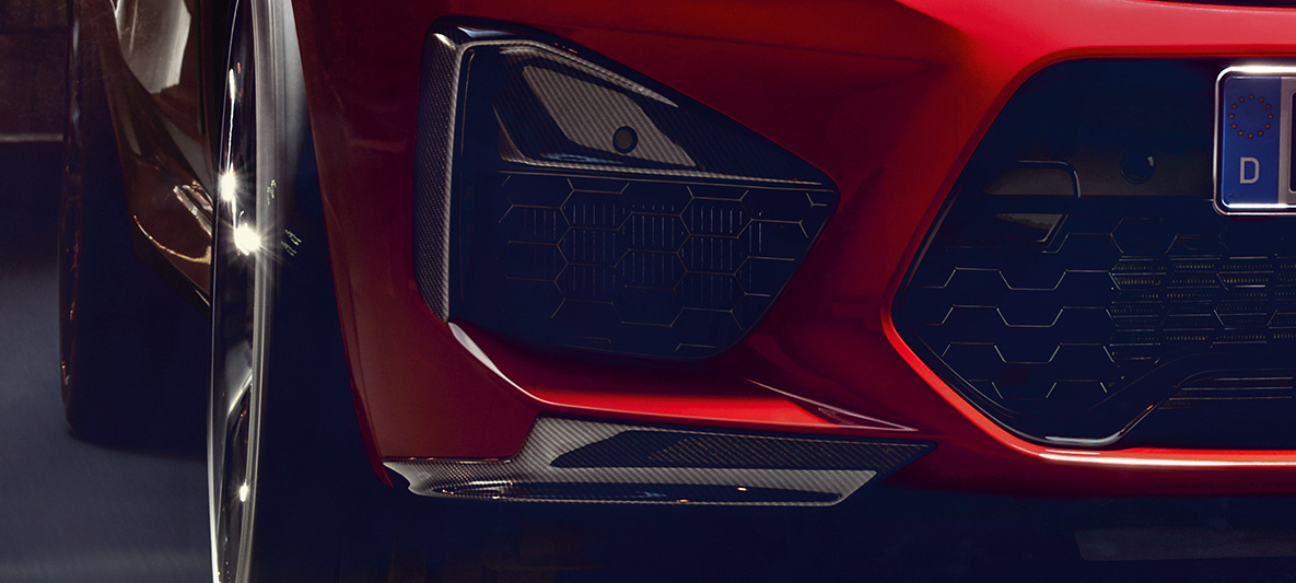 BMW X4 M Competition med dekor på de ytre luftinntakene og aeroblades i karbonfiber. Utvendig design på BMW X4 M Competition i torontorød metallic med M Carbon utvendig designpakke og dekor på de ytre luftinntakene og aeroblades i karbonfiber.