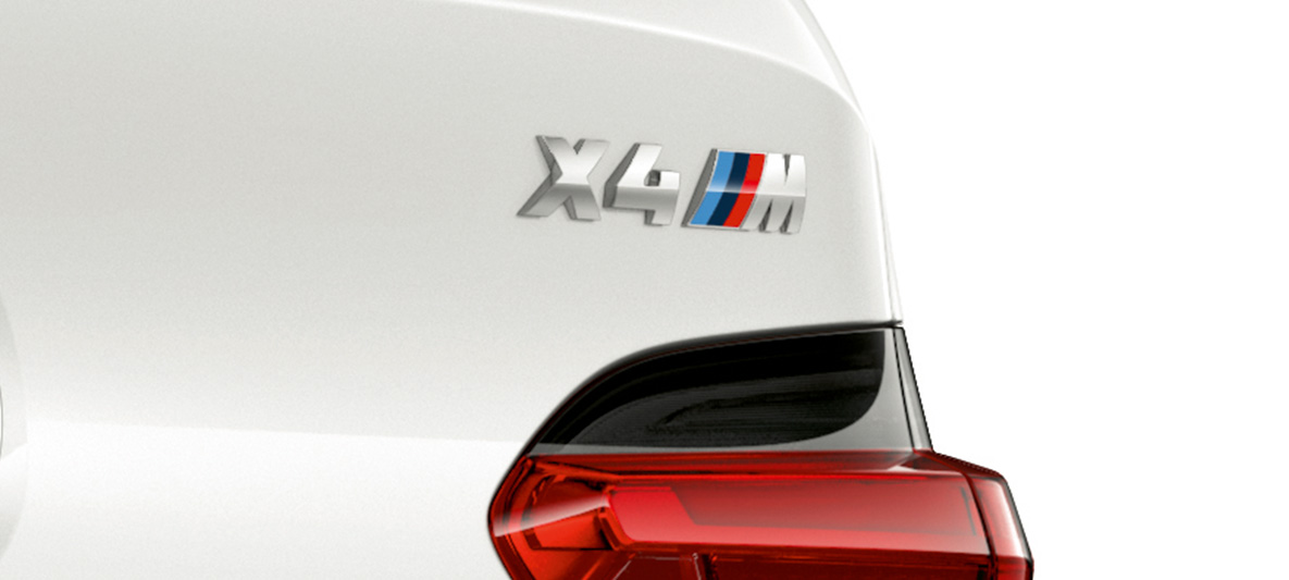 BMW X4 M Competition med modellbetegnelse. Utvendig design på BMW X4 M i alpinhvitt, nærbilde av modellbetegnelse på hekken.