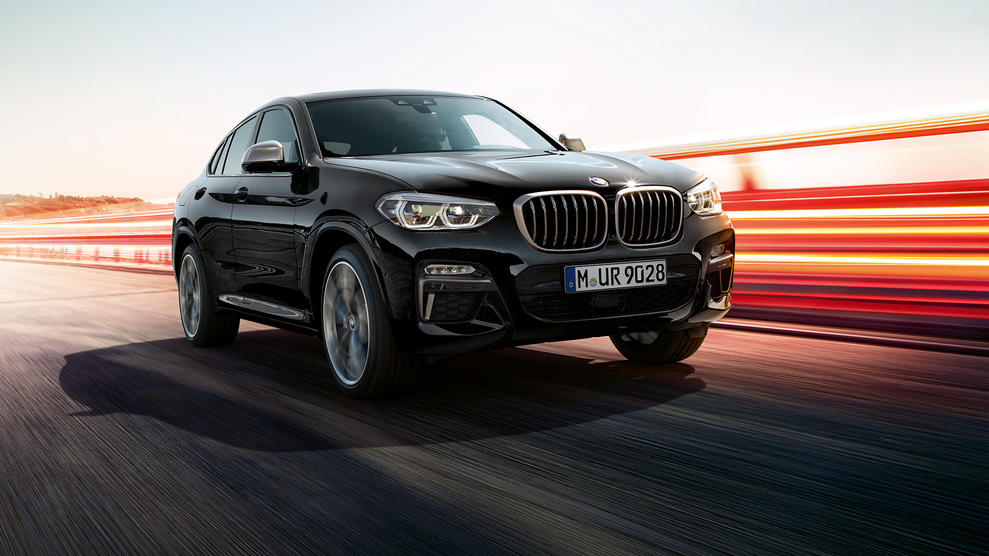 BMW X4 M40i og BMW X4 M40d sett skrått forfra. Utvendig design på BMW X4 M40i og BMW X4 M40d i safirsort metallic sett skrått fra venstre foran med lysstriper.