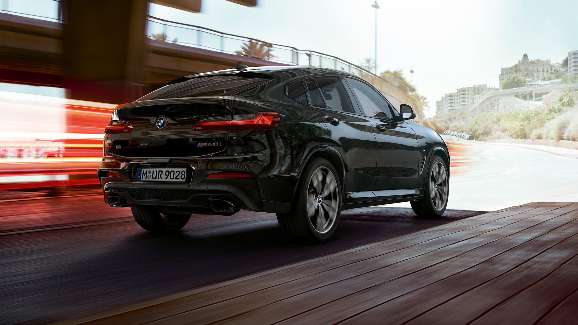 BMW X4 M40i sett skrått bakfra. Utvendig design på BMW X4 M40i i safirsort metallic, sett skrått fra høyre bak med lysstriper.