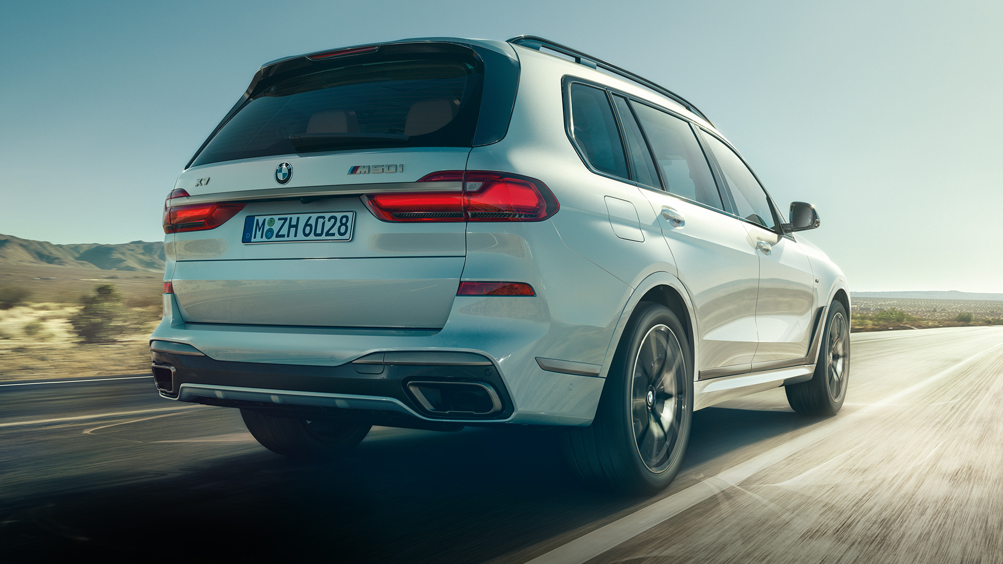 BMW X7 M50i sett bakfra BMW X7 M50i i mineralhvit, i fart, sett skrått bakfra, G07, 2019
