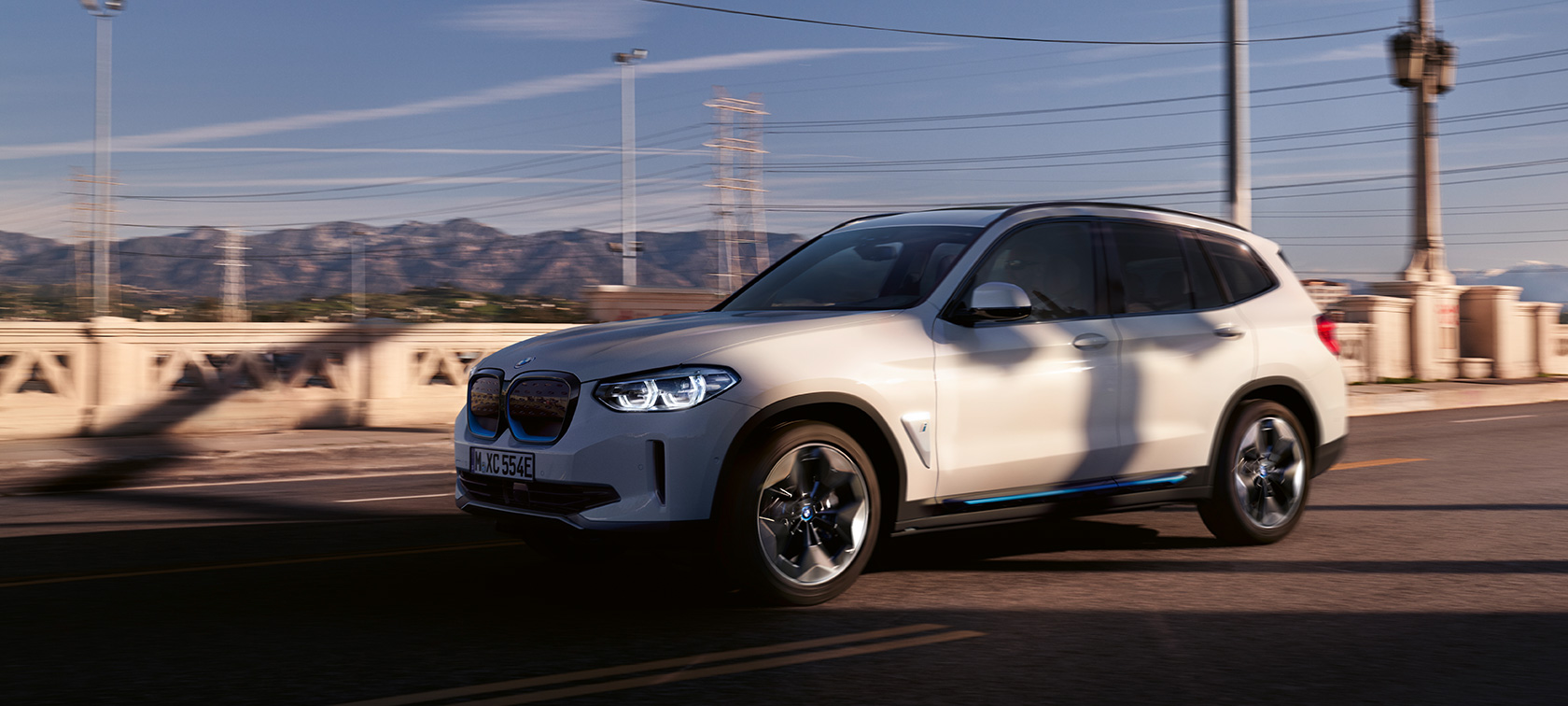 BMW iX3 G08 sett skrått forfra på gaten BMW iX3 G08 2020 Mineralhvit metallic sett skrått forfra kjørende på gaten