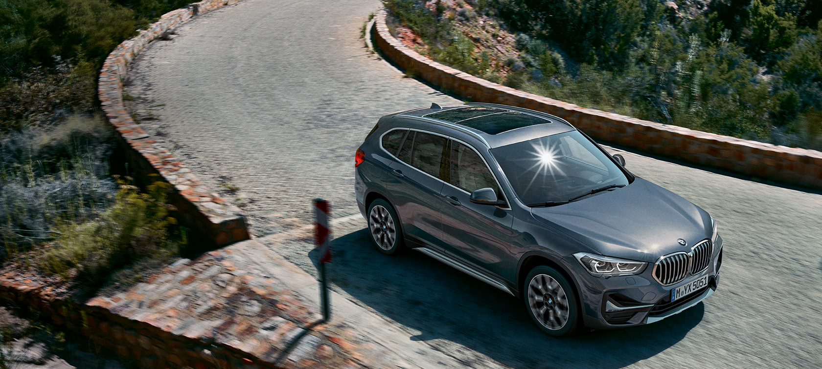BMW X1, sett skrått forfra. BMW X1, sett skrått forfra kjørende foran et fjellandskap.