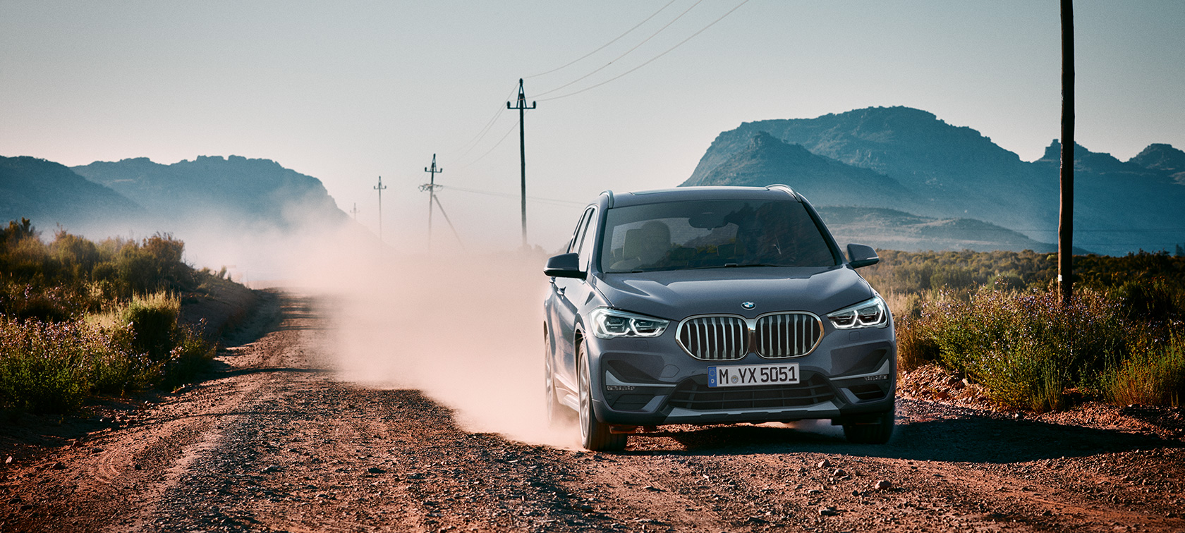 BMW X1, sett skrått bakfra. BMW X1, sett skrått bakfra kjørende foran et fjelllandskap.