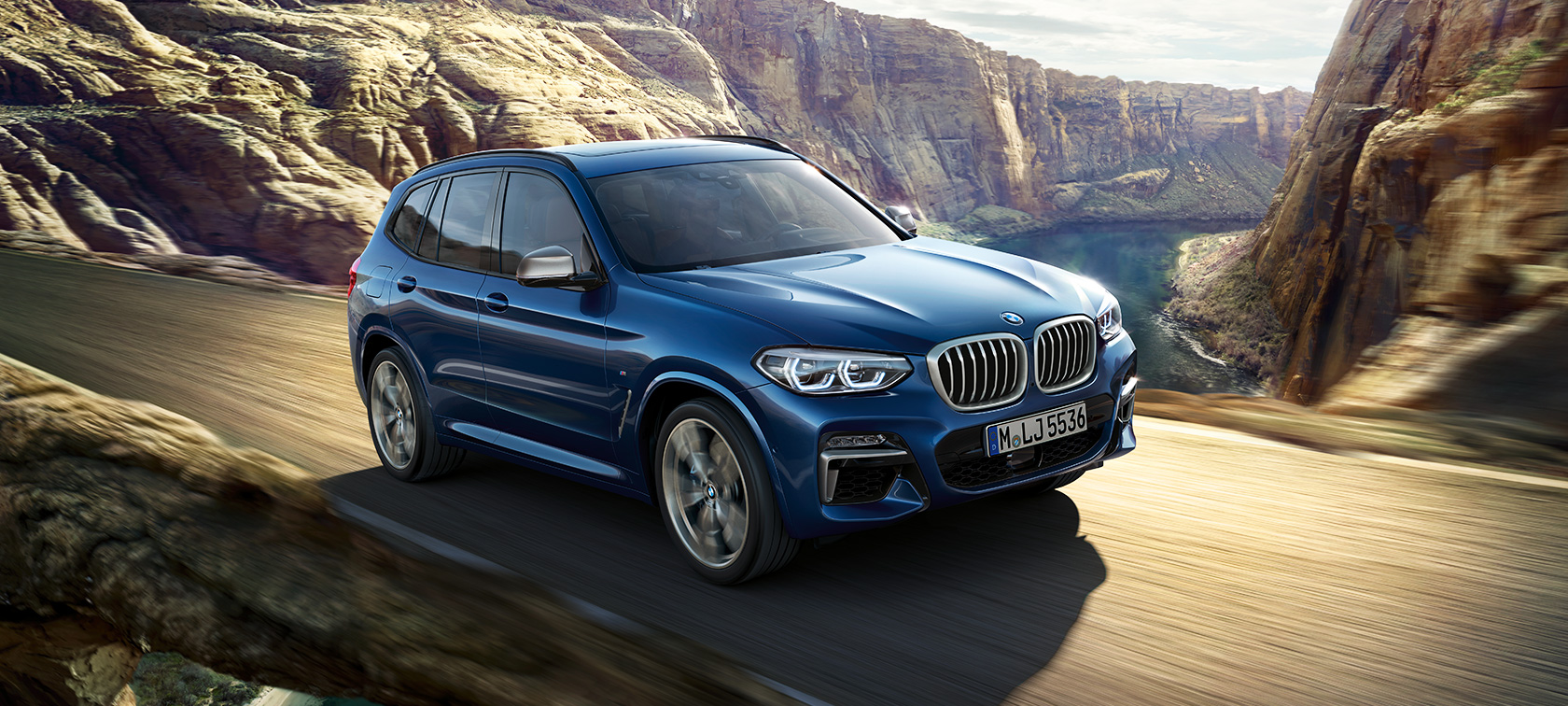 BMW X3 M40i som kjører foran en dal BMW X3 M40i som kjører foran en dal