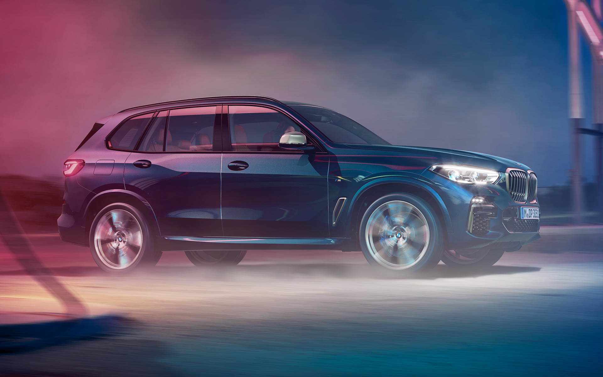BMW X5 M50d som kjører BMW X5 M50d kjører i bylandskap om natten