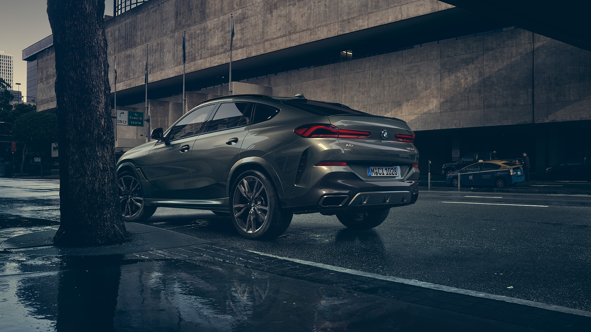BMW X6 eksteriør. BMW X6 i hekkperspektiv foran bylandskap.