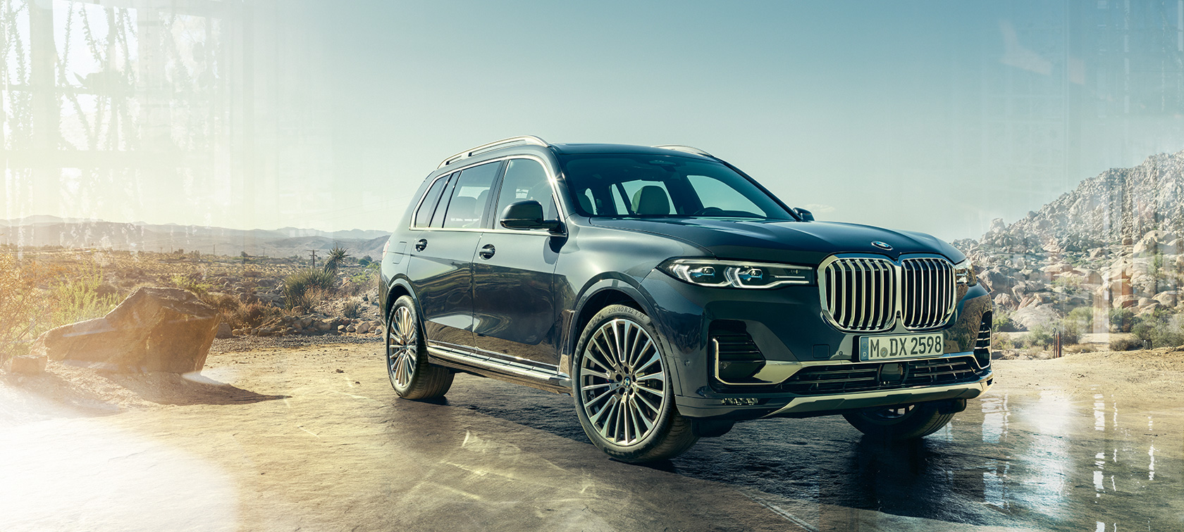 BMW X7 sett skrått forfra fra venstre BMW X7 i antikkgrå stående foran ørkenlandskap, sett skrått forfra fra venstre, G07 2019