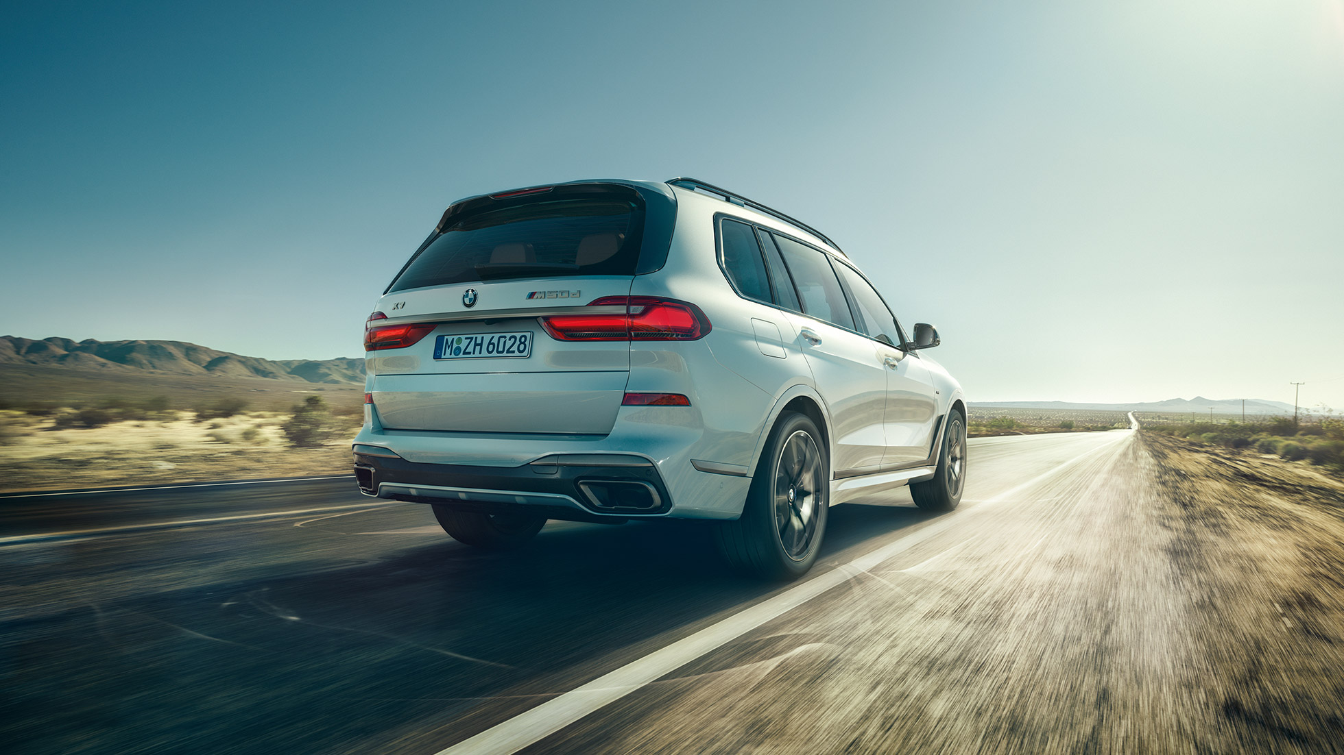 BMW X7 M50d sett bakfra Hvit BMW X7 M50d i fart sett bakfra
