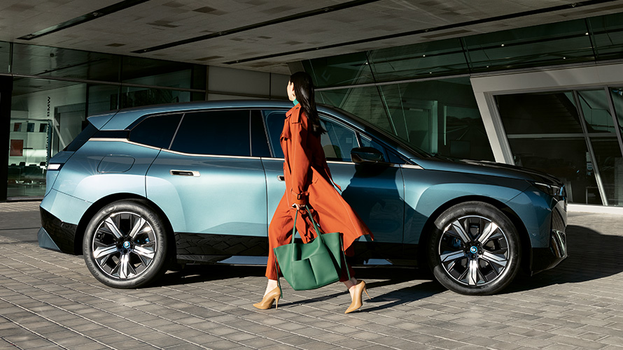 Bruk av BMW Digital Key Bruk av BMW Digital Key BMW iX i20 Sett fra siden med kvinne i forgrunnen