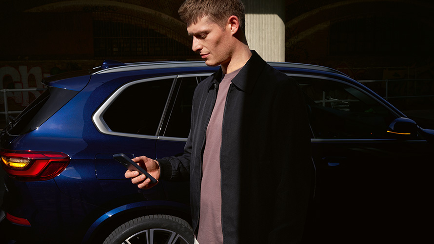 BMW Digital Key – Autorisere opp inntil fem brukere BMW Digital Key Autorisere opp inntil fem brukere Mann med smarttelefon foran BMW X5