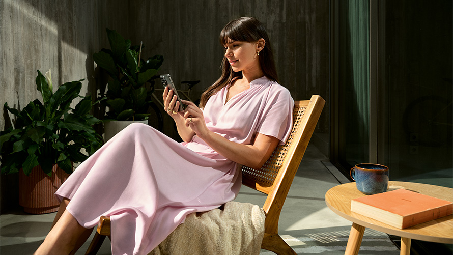 Kvinne i rosa kjole på en stol med smarttelefon i hånden, Remote Inside View Remote Inside View, Kvinne i rosa kjole på en stol med smarttelefon i hånden