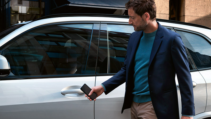 Digital nøkkel En mann åpner sin BMW med digital nøkkel på smarttelefonen