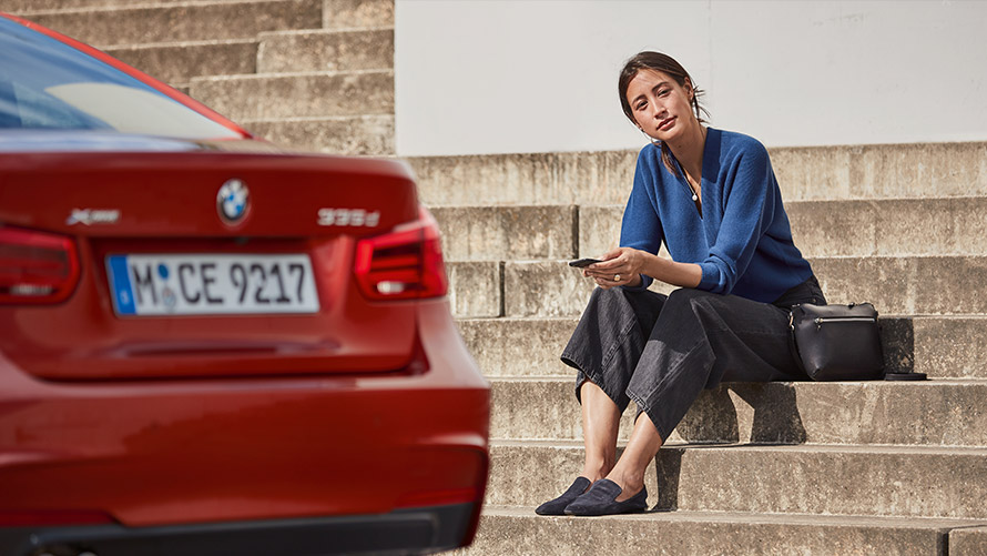 Service og veihjelp Kvinne sitter foran en rød BMW og bruker service og veihjelp