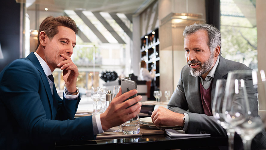 Administrer favorittmålene dine To menn på en restaurant bruker funksjonen for å administrere favorittmålene sine på smarttelefonen