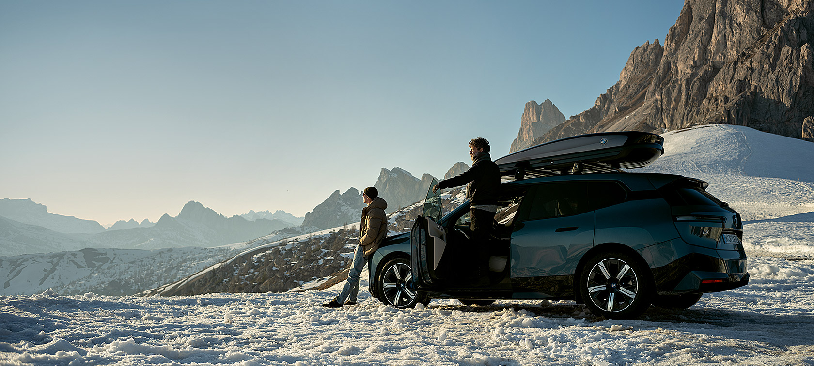 BMW Originaltilbehør og BMW Service for høst og vinter Menn med BMW iX i et snølandskap