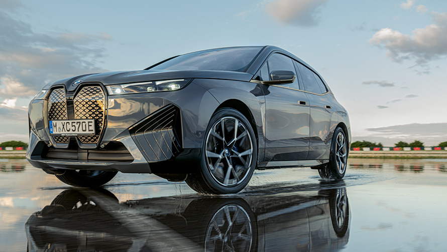 BMW felger, BMW iX (i20) sett skrått forfra på våt veibane BMW felger, BMW iX (i20) sett skrått forfra på våt veibane