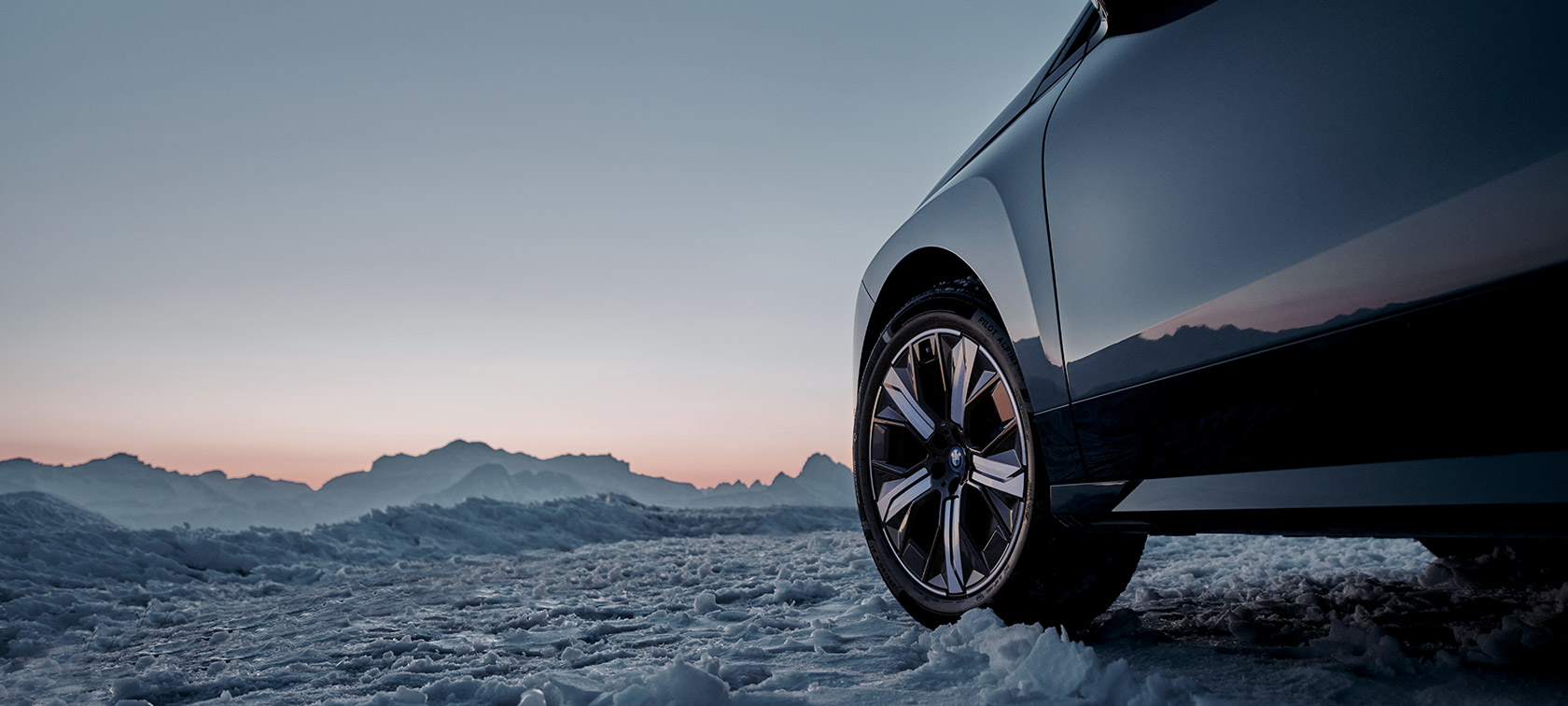 BMW Originalfelger på BMW iX (I20) i snø foran fjell BMW Originalfelger på BMW iX (I20) i snø foran fjell