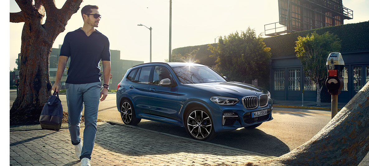 Mann med solbriller foran blå BMW Mann med solbriller foran blå BMW