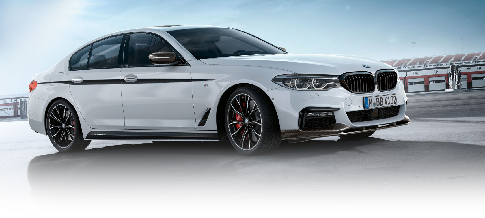 BMW 3-serie Sedan med M Performance Parts. BMW 3-serie Sedan sett fra siden på en parkeringsplass mot blå himmel.