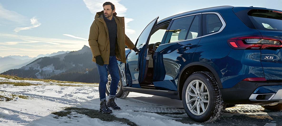 Mann med solbriller foran blå BMW Mann med solbriller foran blå BMW