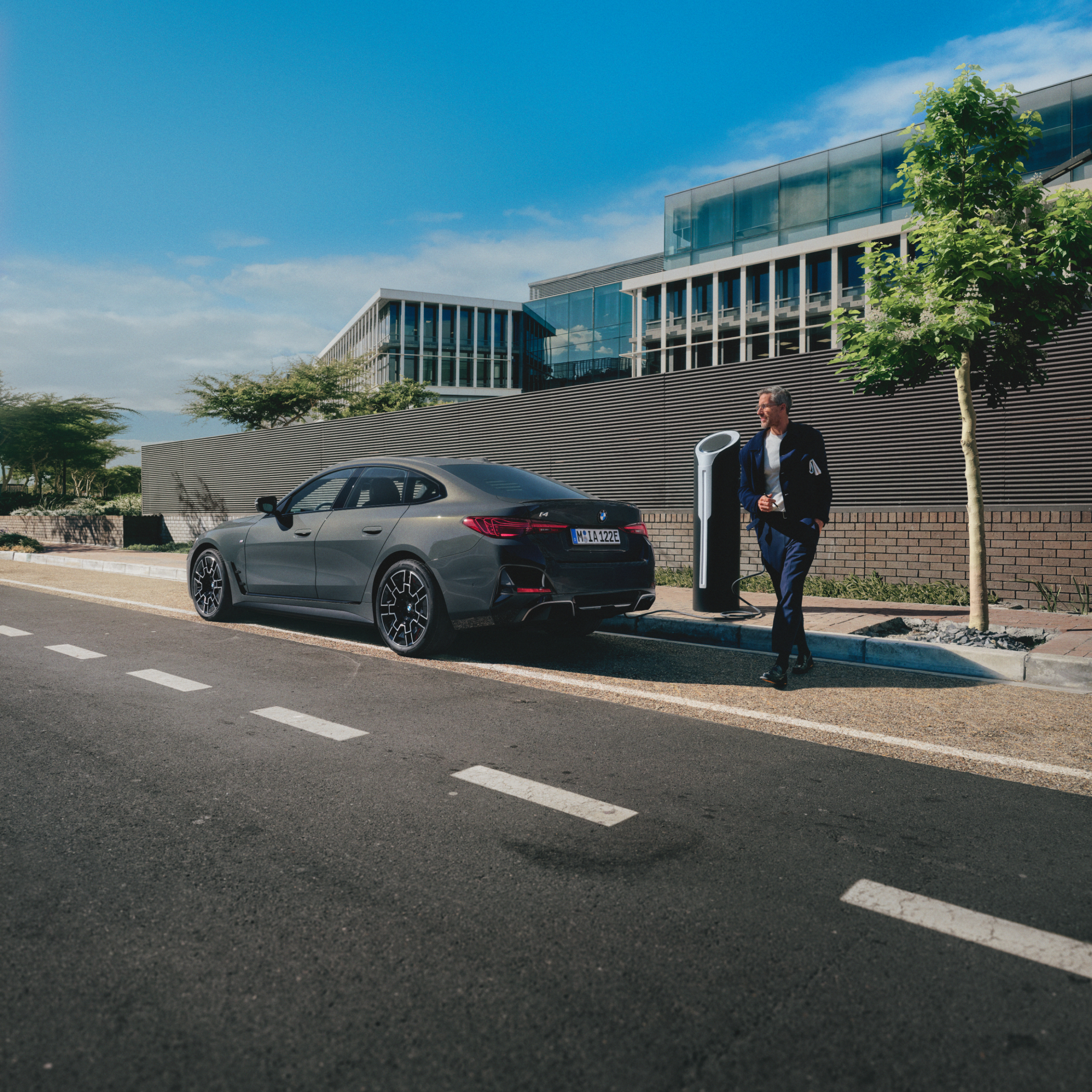 Person som står bak en ladende BMW ved siden av veien